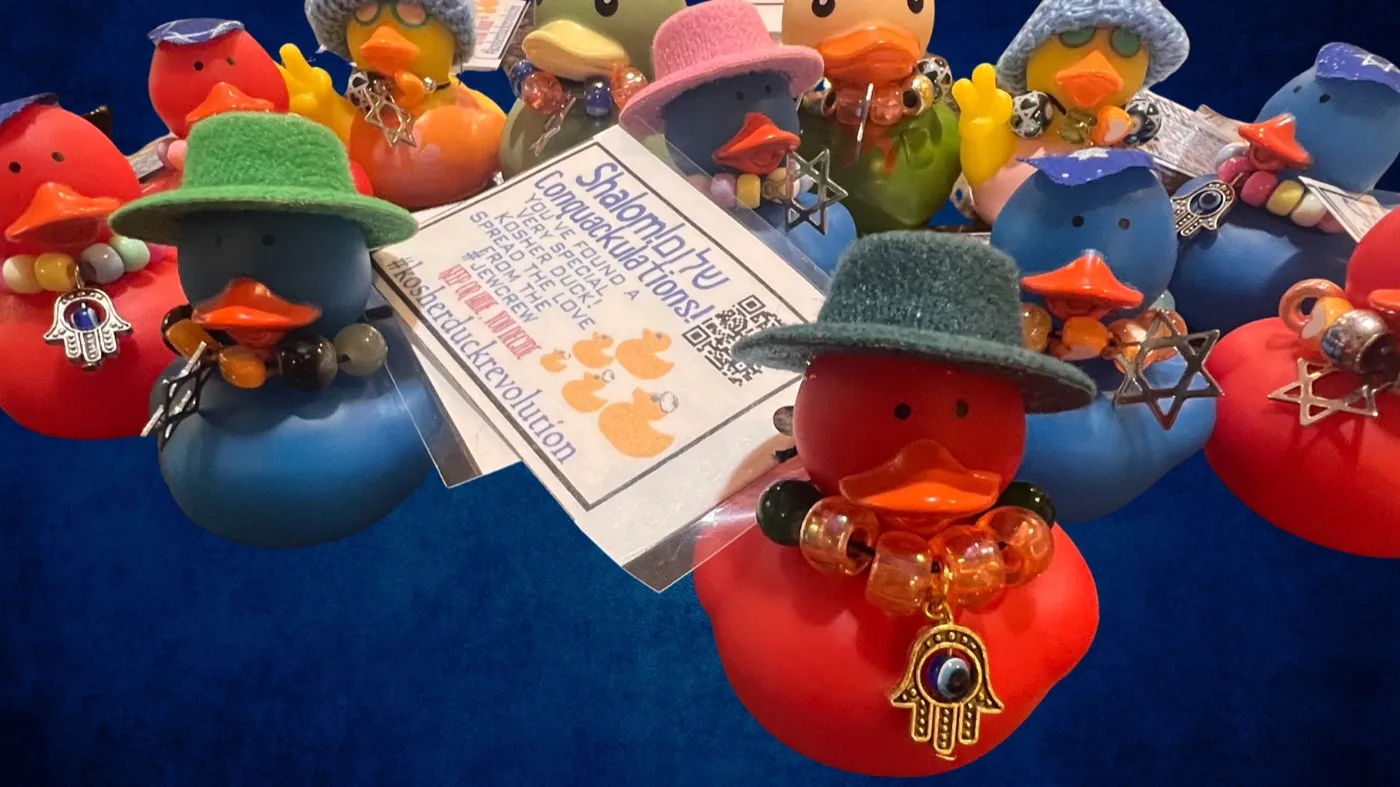 A whole flock of Kosher Duck Revolution rubber ducks in little felt hats, gathered around a Shalom card, some wearing hamsa and Star of David charms