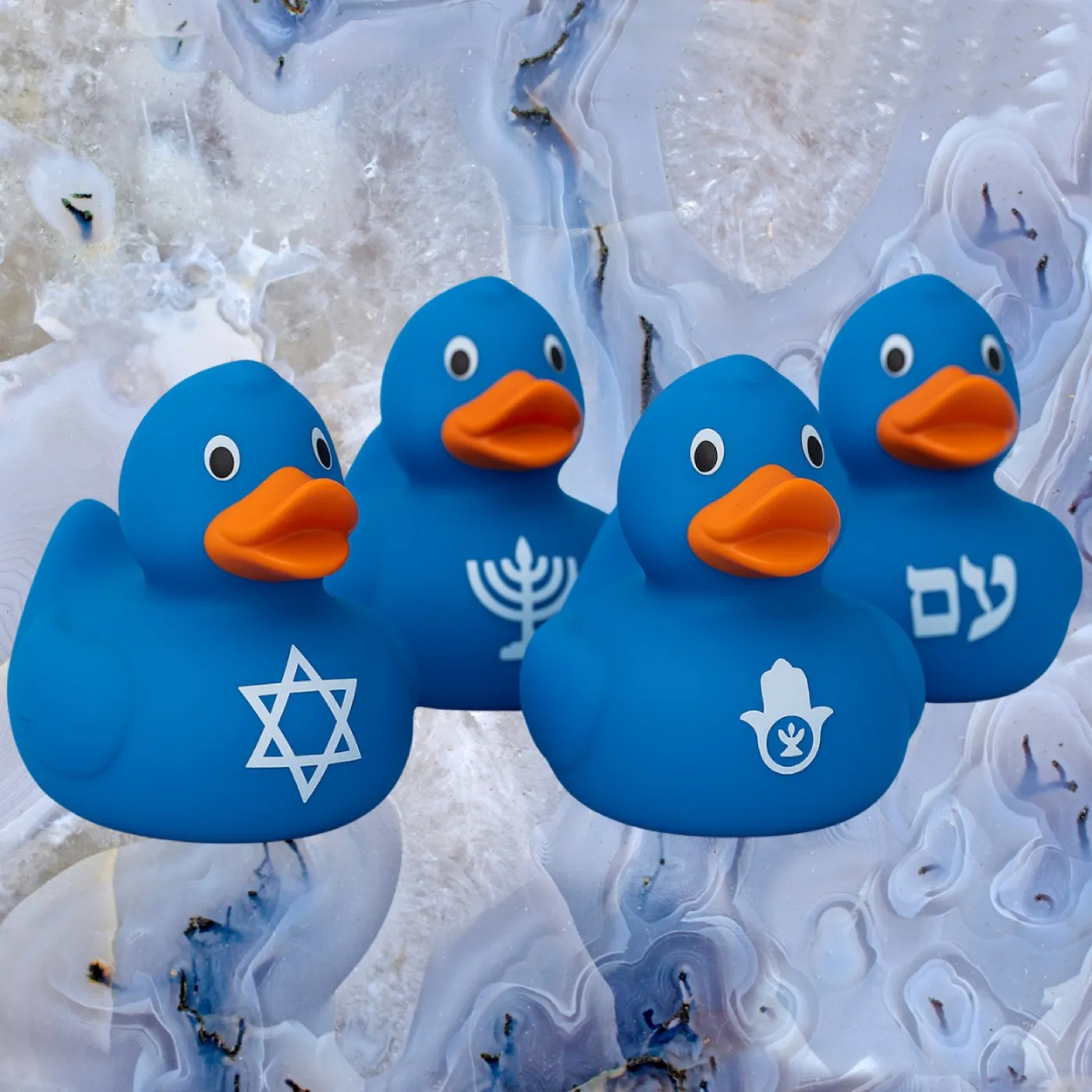 A flock of bright-blue Kosher Duck Revolution rubber ducks — each with a Star of David, a hamsa, or עם on its chest — clustered together